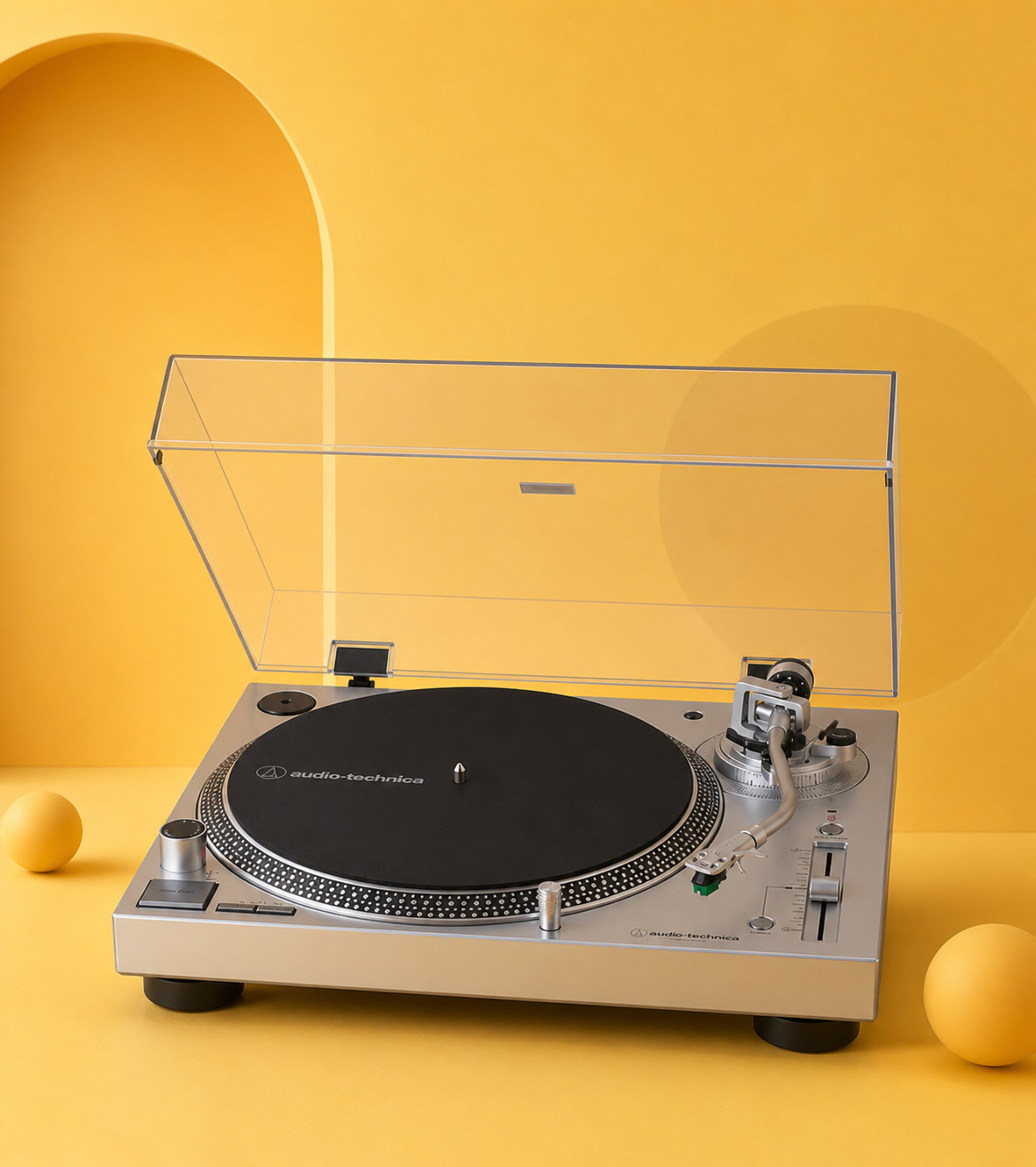 Vintage silver turntable with clear dust cover on a bright yellow background