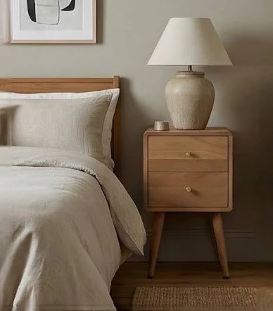 Wooden bedside table with lamp beside modern bed
